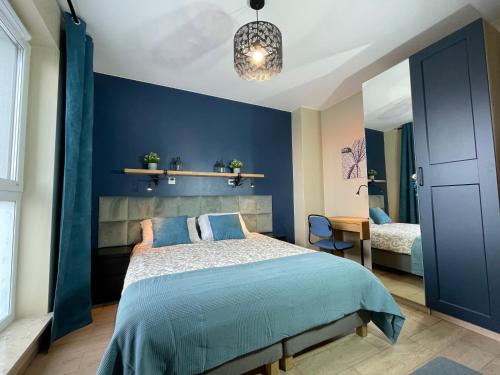- une chambre dotée d'un mur bleu avec un lit et un bureau dans l'établissement Superior Baltea 3 rooms, Beach 800m, AirCondition, à Gdańsk