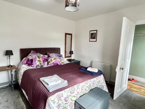 a bedroom with a bed with a purple bedspread at Lottie’s Cottage, Rhynie, Aberdeenshire in Rhynie