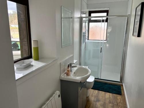 a white bathroom with a sink and a shower at Lottie’s Cottage, Rhynie, Aberdeenshire in Rhynie