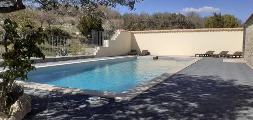 una piscina en un patio trasero con sillas alrededor en Gîte L'ESCOUSSOU 6p, 4ch, 120m2, charme et nature, piscine chauffée, sud Ardèche, en Joyeuse