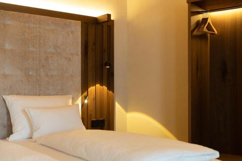 a bedroom with a white bed with a wooden headboard at Camino Rustic Chic Hotel in Livigno