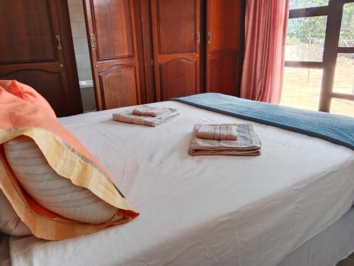 a bed with two pillows and towels on it at Nakhah Guesthouse - Private Interior in eMalahleni
