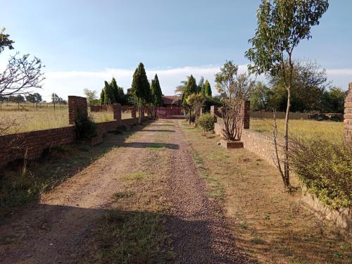 a dirt road with trees and a wall at Nakhah Guesthouse - Private Interior in eMalahleni