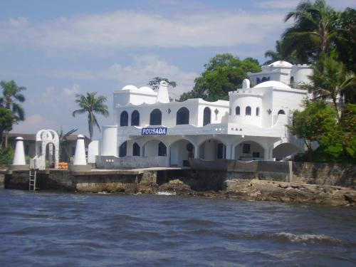 una casa blanca en el agua junto al agua en Pousada Castelinho Caiobá, en Caiobá