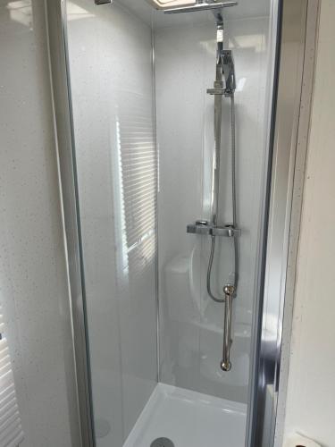 um chuveiro com uma porta de vidro na casa de banho em Colemans Caravans Golden Anchor Caravan Park em Chapel Saint Leonards