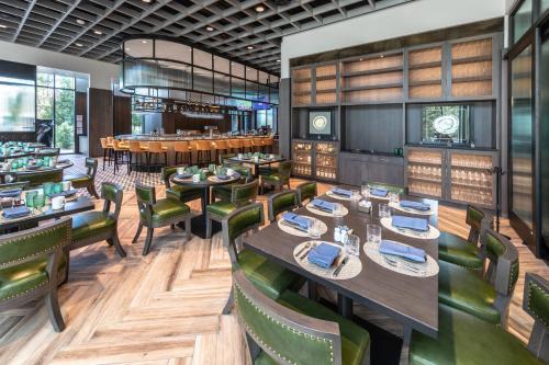 a restaurant with wooden tables and green chairs at Houston CityPlace Marriott at Springwoods Village in The Woodlands