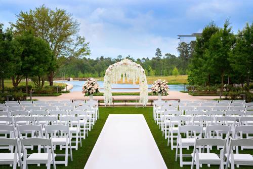 a wedding ceremony with a white altar and white chairs at Houston CityPlace Marriott at Springwoods Village in The Woodlands