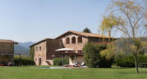 a large stone building with a table and an umbrella at Masia Quelet in La Vall de Bianya
