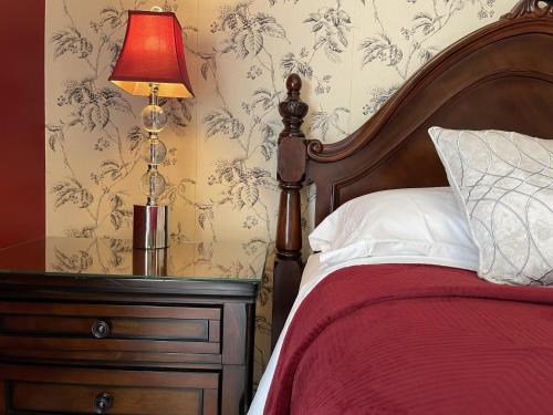 a bedroom with a bed and a lamp on a dresser at Darlington House Bed and Breakfast in Niagara on the Lake