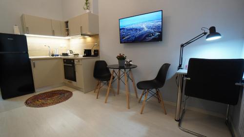 a kitchen with a table and chairs and a television on the wall at City Life Metro Ambelokipi in Athens