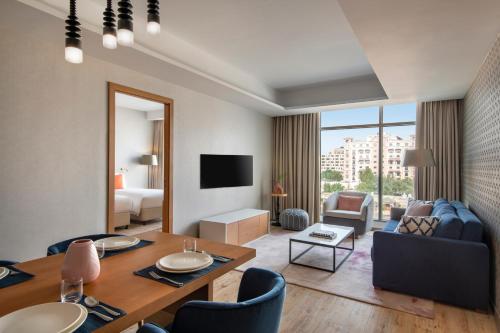 Abesq Doha Hotel and Residences في الدوحة: غرفة مع طاولة طعام وغرفة معيشة