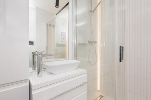 a white bathroom with a sink and a shower at Apartament Bielany 3 min from metro with 5-meals per day customisable diet catering and free parking in Warsaw