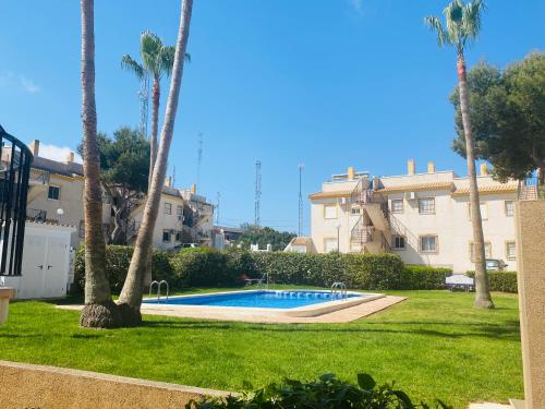 a pool in a yard with palm trees and a building at Saint James park 2 dormitorios in Orihuela