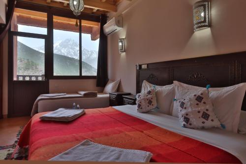 a bedroom with a large bed with a red blanket at DAR ATLAS CHARME in Imlil