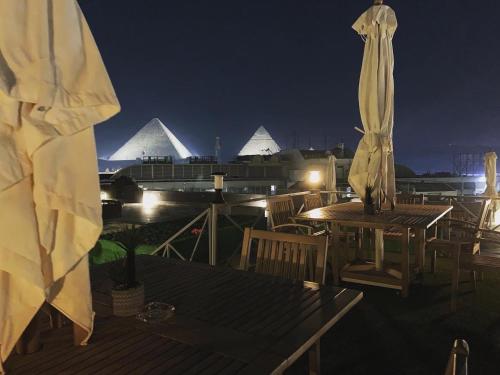 a rooftop deck with a table and chairs and pyramids at Locanda Museum Hotel in Giza