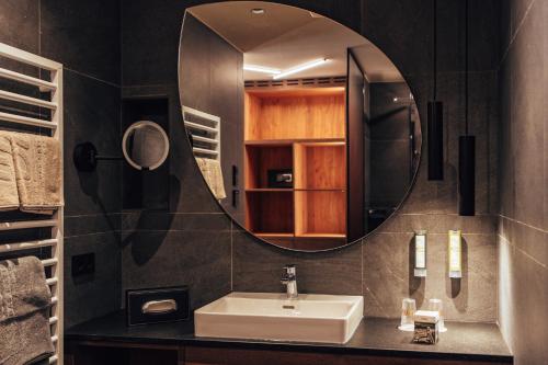 a bathroom with a sink and a mirror at Dilly - Das Nationalpark Resort in Windischgarsten