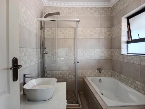 y baño con bañera y lavamanos. en Nakhah Guesthouse - Double Room en Witbank