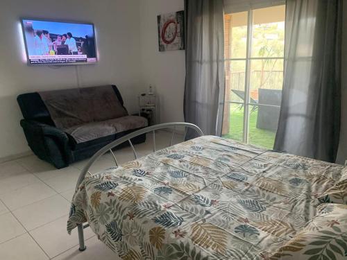 - une chambre avec un lit, une chaise et une télévision dans l'établissement Bel appartement à 100 m du port, à Porto-Vecchio