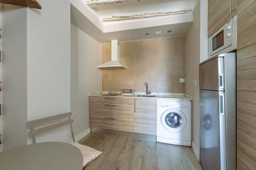 a kitchen with a washing machine and a sink at Apartamentos Vino Tinto y Restaurante Tomate Rosa in Adahuesca