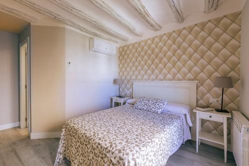 a bedroom with a bed and two tables and a wall at Apartamentos Vino Tinto y Restaurante Tomate Rosa in Adahuesca