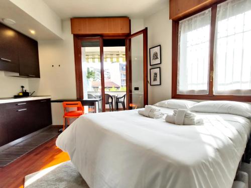 a bedroom with a large white bed and a kitchen at Cozy Apartment with large exclusive terrace in Milan