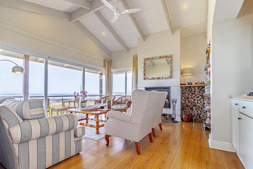 138 Marine Beachfront Guesthouse في هيرمانوس: غرفة معيشة مع أريكة وطاولة وكراسي
