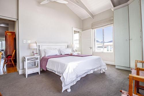 a white bedroom with a large bed and a window at 138 Marine Beachfront Guesthouse in Hermanus