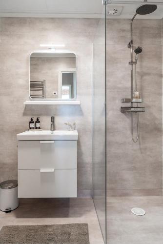 a bathroom with a sink and a mirror and a shower at Munksund Apartments Villa in Piteå
