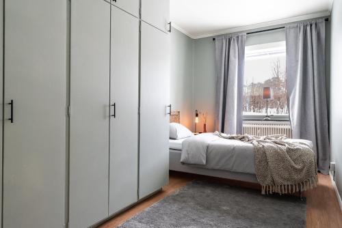 a bedroom with white cabinets and a bed with a window at Munksund Apartments Villa in Piteå