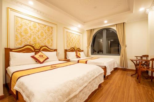 a hotel room with two beds and a table at TRÍ TÂM HOTEL - Khách sạn TRÍ TÂM Bến Lức in Bến Lức