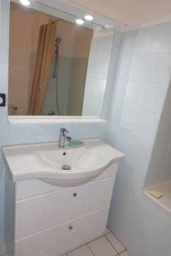 ein weißes Badezimmer mit einem Waschbecken und einem Spiegel in der Unterkunft Topaze Pei - T1 - 2 personnes in Saint-Denis