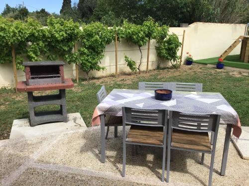 une table et des chaises avec une table et un grill dans l'établissement La petite maison des Muses Arles, à Arles