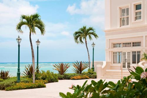 a building with palm trees in front of the ocean at Moana Surfrider, A Westin Resort & Spa, Waikiki Beach in Honolulu