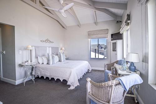 a bedroom with a bed and a chair and a window at 138 Marine Beachfront Guesthouse in Hermanus