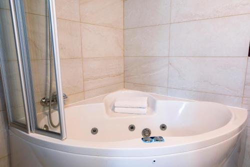 a white bath tub in a bathroom with a shower at Apartamentos Vino Tinto y Restaurante Tomate Rosa in Adahuesca