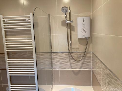 a shower with a shower head in a bathroom at 2 Malt Kiln Cottages in Grizebeck