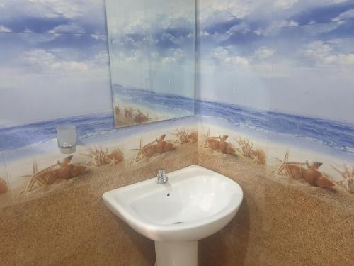 a bathroom with a sink and a painting of the beach at Nature guesthous in Midigama