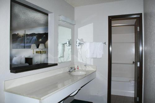 Baño blanco con lavabo y espejo en Days Inn by Wyndham Sioux Falls, en Sioux Falls