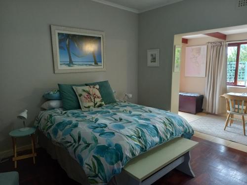 a bedroom with a bed and a table and a window at Sunshine Cottage in Cape Town