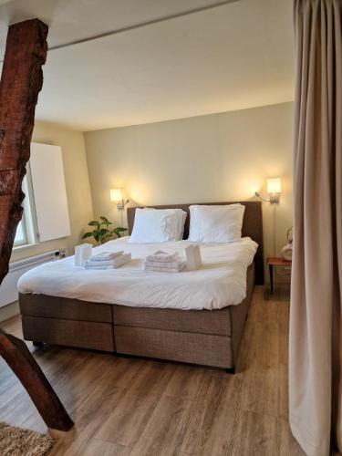 een slaapkamer met een groot bed met witte lakens en kussens bij De Hofstee in Maastricht