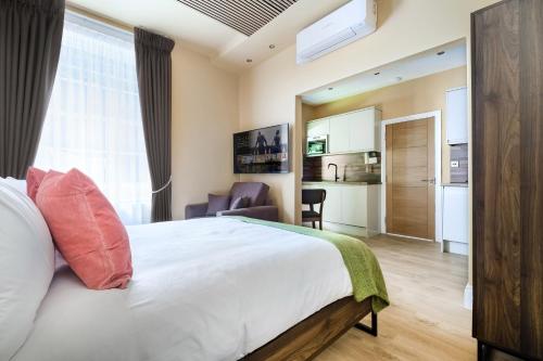 Cet appartement comprend une chambre avec un grand lit blanc et une cuisine. dans l'établissement Luxury Apartment in the heart of Central London, à Londres