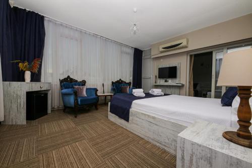 una camera d'albergo con un letto, delle sedie e una televisione di MELODİ BUTİK OTEL a Edremit