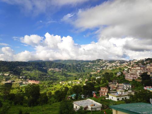 a town on a hill with clouds in the sky at MangalMurti Himalyan Hotel in Almora