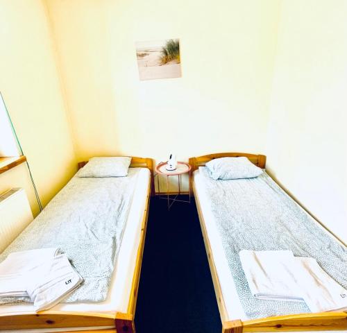two twin beds in a room with a table at Express Guest House in Klaipėda