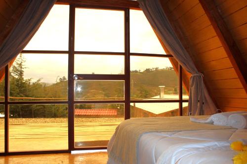 Cama en habitación con ventana grande en GLAMPING NAKAMA Cajamarca, en Cajamarca