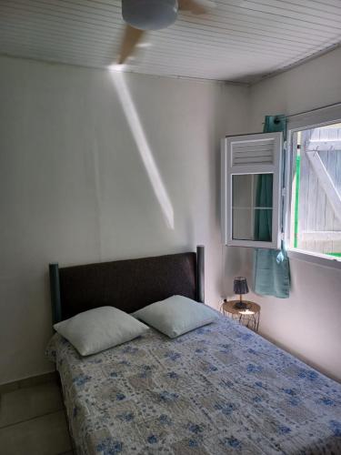 1 dormitorio con 1 cama con 2 almohadas y ventana en Maison tartanaise, en La Trinité