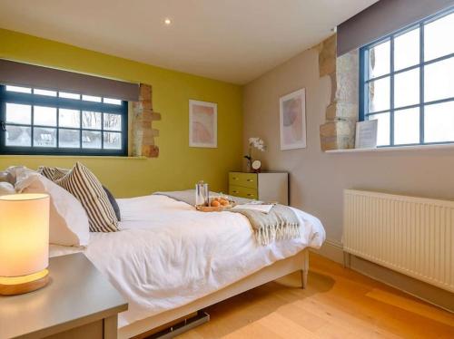 a bedroom with a large white bed with yellow walls at Woodmill Bakewell Riverside in Bakewell