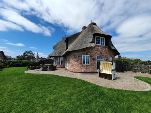 a thatched house with a lawn in front of it at Hotel Duene in Rantum