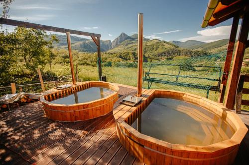 two wooden tubs on a deck with a view of mountains at Popas 8 Odăi in Poiana Aiudului
