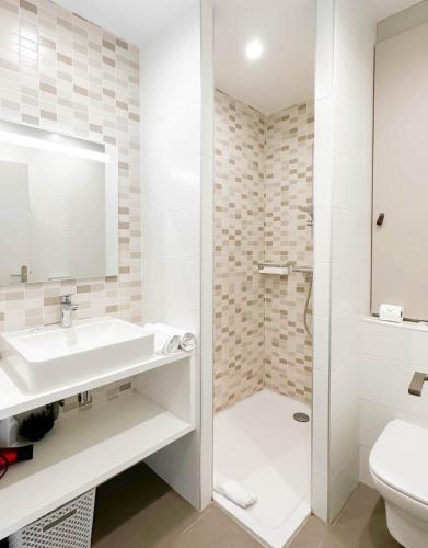 une salle de bain blanche avec un lavabo et une douche dans l'établissement Central Park au centre ville, à Annecy